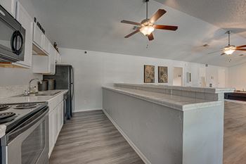 A kitchen with a stove top oven and a fan hanging from the ceiling.
